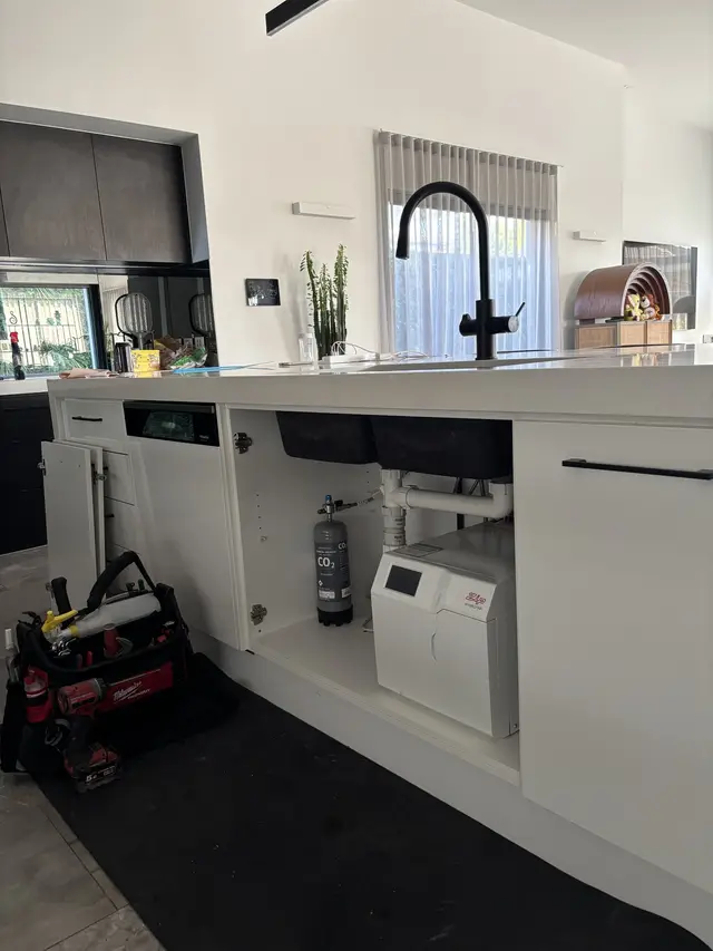 Black Zip HydroTap on a kitchen island with the chiller unit and CO2 cylinder installed in the cabinet below