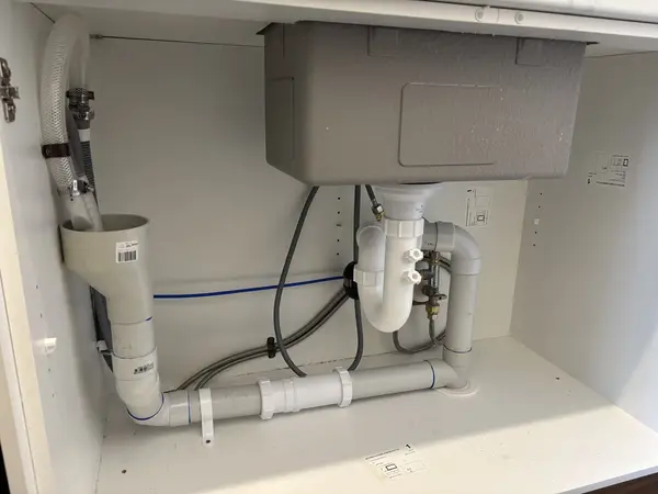 New plumbing under a kitchen sink: sink waste and trap, dishwasher drain hose and water connections
